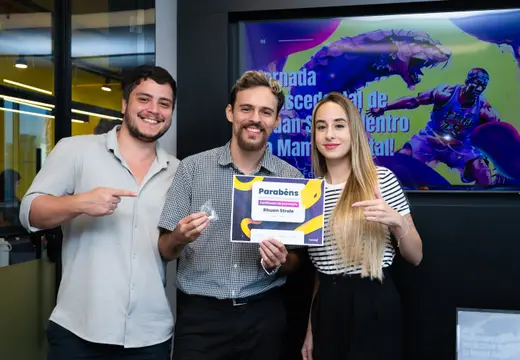 Rhuan Strele com clientes e certificado em frente a painel de evento.