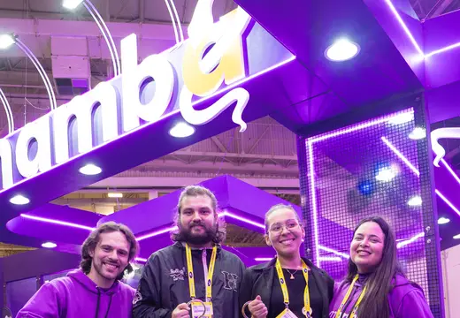 Equipe Mamba em estande iluminado com identidade roxa.